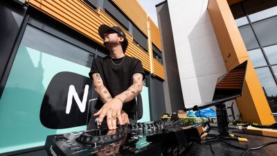 En DJ som står ved et miksebord og styrer musikken.