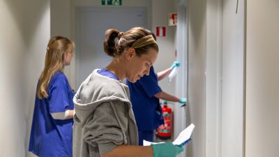 tre mennesker står i en gang med kontrollskjemaer.