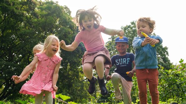 Fire barn som leker og hopper i en park.