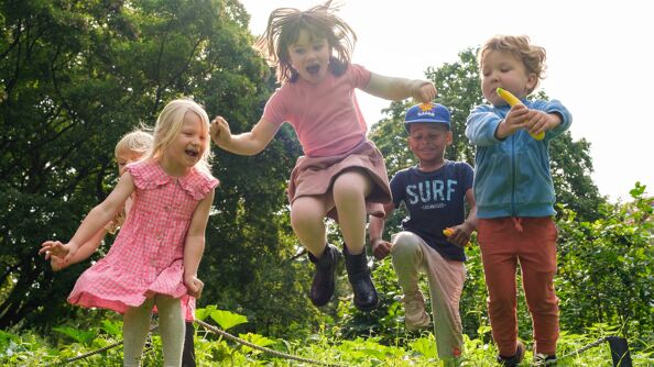 Fire barn som leker og hopper i en park.