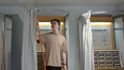 Person utenfor et valgavlukke som trekker for gardinen