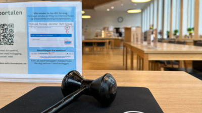 Bildet viser en svart klubbe som ligger på et bord i en møtesal.