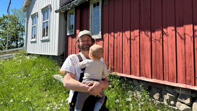 Mann med baby på gård.
