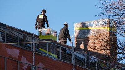 Bygningsarbeidere på toppen av et hustak.