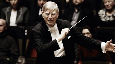 Mann i dress og holder en dirigentstav