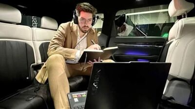 Mann sitter i bil og ser på laptop.