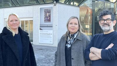 To damer og en mann foran bygning.