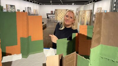 Dame tittet mellom et kunstverk av noen som likner klosser.