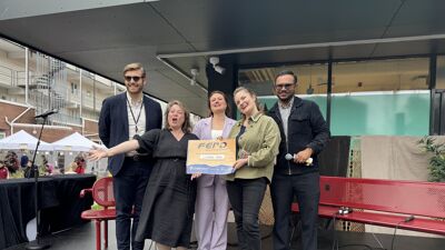 Fem glade mennesker på en scene med et skilt i hendene.