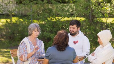Fire voksne mennesker sitter rundt et bord og snakker sammen.