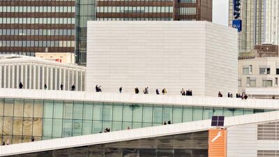 Operahuset er avbildet på avstand. Det er flere mennesker som nyter utsikten fra taket.