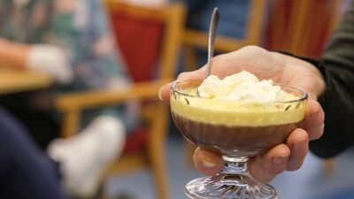 En hånd som holder en bolle med sjokoladepudding