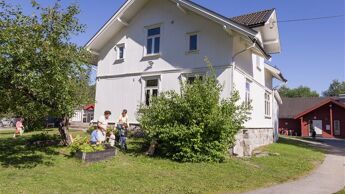 Et hvitt trehus med hage foran