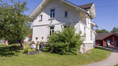 Et hvitt trehus med hage foran