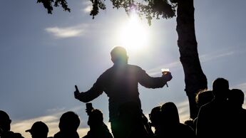 Flere silhuetter av mennesker som koser seg og strekker seg opp mot sollyset.