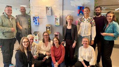 Teamet med fagpersoner i Fact- ung samlet foran en av veggene med fuglekasse.r