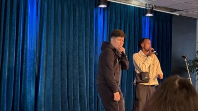 To unge menn på scene synger i mikrofoner