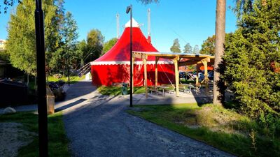 Et rødt sirkustelt i midten av en park.