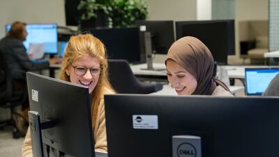 To kollegaer jobber sammen ved siden av dataskjermer.