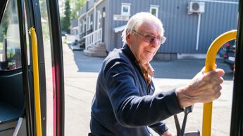 Eldre mann på vei ut av en buss