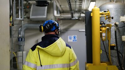 Mann i arbeidstøy med ryggen til inne på Romerike biogassanlegg.