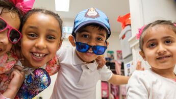 Fire barnehagebarn som smiler og ser inn i kamera.