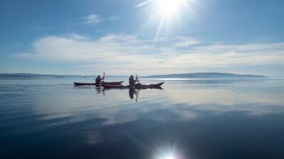 To personer padler kajakk på en blikkstille Oslofjord