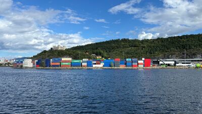 Containere i stabler langs fjorden foran den grønne Ekebergåsen.