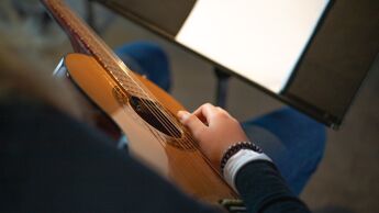 En gitar sees skrått ovenfra med hånd over strengene