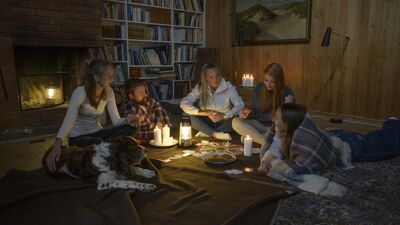 Familie som sitter samlet på gulvet under et strømbrudd.