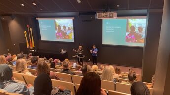 Byrådens står på scenen, med tegnespråktolk ved siden av seg, foran publium sittende i auditoriet.