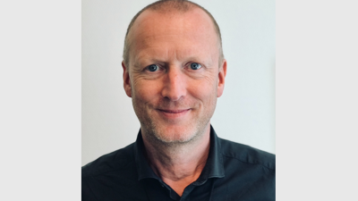 Mann i sort skjorte, lite hår, smiler