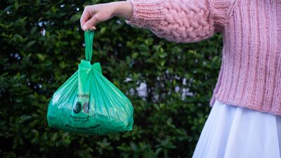 Hånd som holder en grønn avfallspose