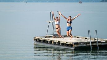 To jenter hopper fra en badebrygge i Oslofjorden