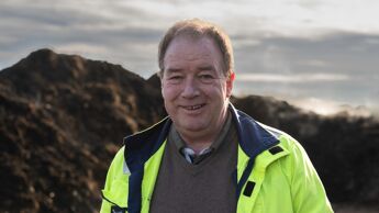 Mann med gul jakke foran jordhaug