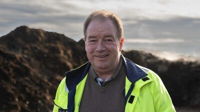 Mann med gul jakke foran jordhaug