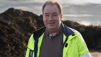 Mann med gul jakke foran jordhaug