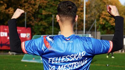 Fotballspiller med drakt med teksten "fellesskap og mestring"