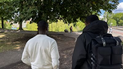 Bilde av "Mohammed" og Mahad Abdi Jama i uteseksjonen. Begge står med rygge mot kamera i en park.
