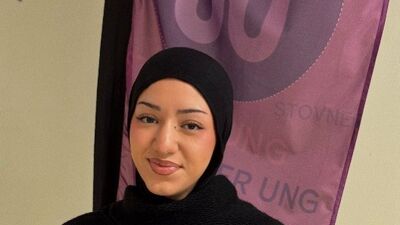 En ung kvinne i sjal som smiler.