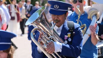 Jente i blå uniform spiller tuba. Skoleskorps i 17. mai-toget 2022.