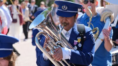 Jente i blå uniform spiller tuba. Skoleskorps i 17. mai-toget 2022.