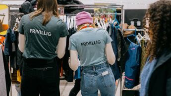 Vi ser to personer med ryggen til med tskjorter som det står Frivillig på.