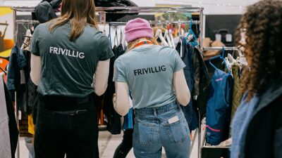 Vi ser to personer med ryggen til med tskjorter som det står Frivillig på.