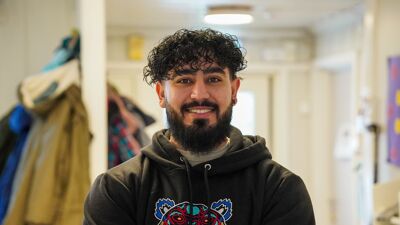 Portrettbilde av Hassan Butt som står i gangen hos en barnehage.