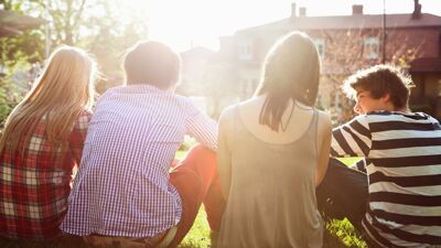 Fire ungdommer som sitter i gresset