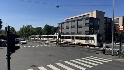 Bilde av Vinderenkrysset. T-banen på vei mot Frognerseteren, bil som venter på grønt lys og forgjenger som venter på grønt lys for å krysse sporene mot Vinderen sentrum.