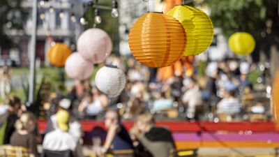 Rislamper i forskjellige farger henger over folk som koser seg på uteservering