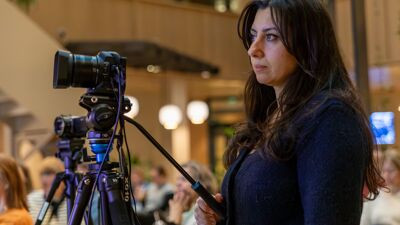 Hüsran står og filmer et seminar.