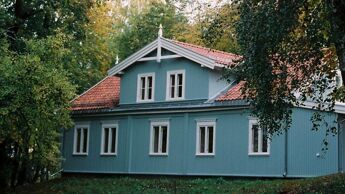 Bilde av Nabolagshuset Nordre Trosterud gård, en turkis trevilla omringet av trær, som brukes til frivillig aktivitet.